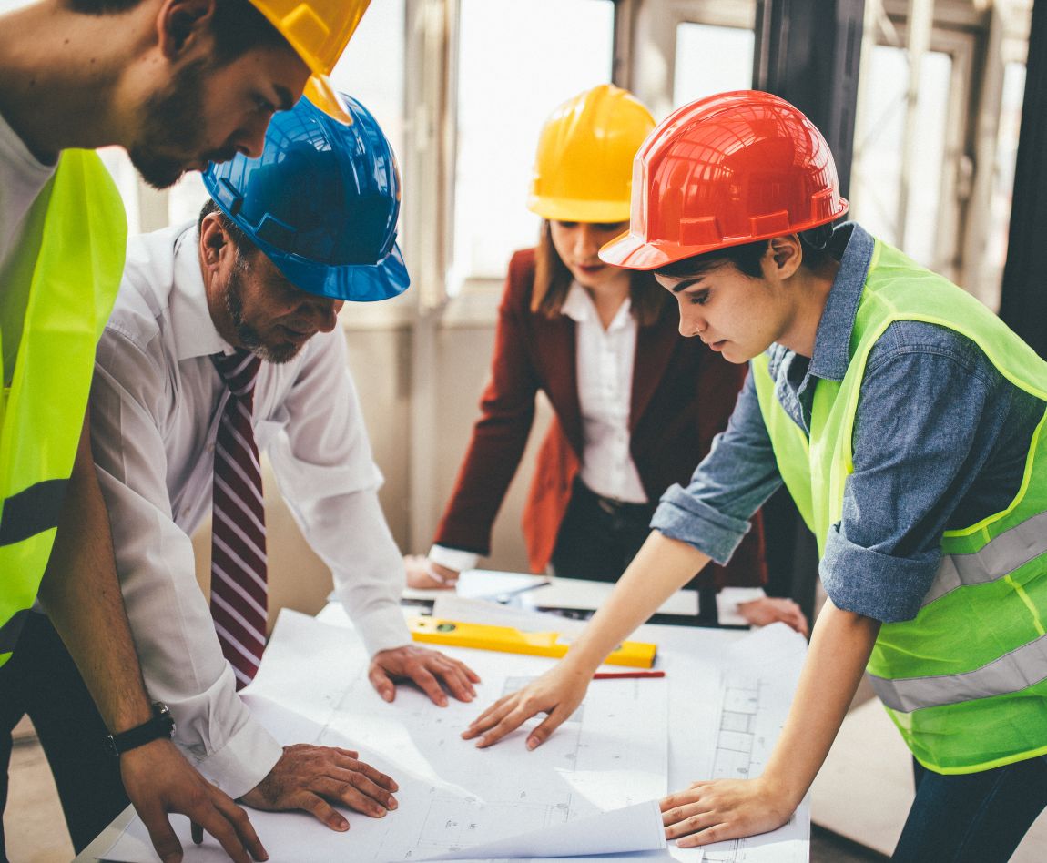 Équipe d'ingénieurs et d'architectes en réunion de chantier examinant des plans techniques.