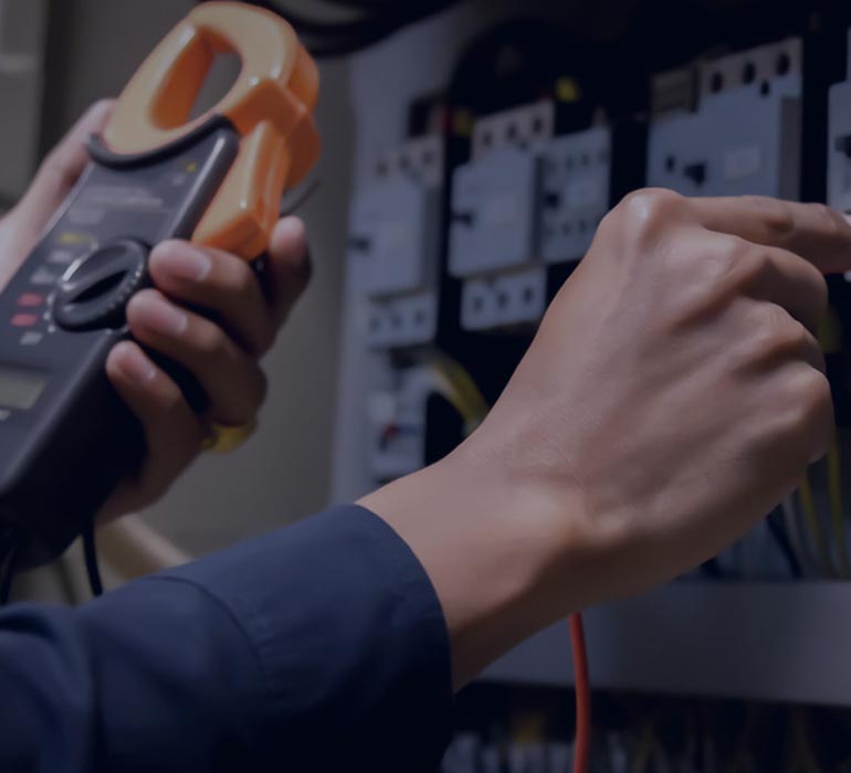 homme intervenant sur un tableau électrique avec un appareil de contrôle