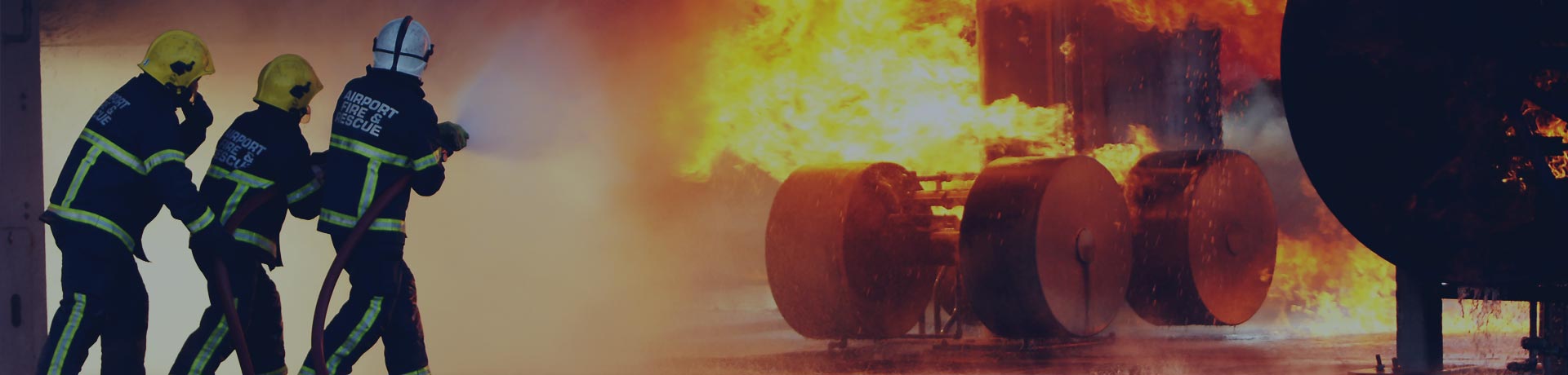 3 pompiers avec une lance à eau éteignant un feu sur le train d'atterrissage d'un avion