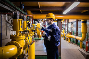Photo Heating plant gas pipe installation. Industrial or power plant worker checking gas consumption.