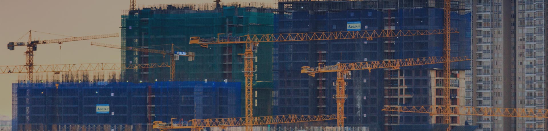 varias grúas frente a un gran complejo de edificios