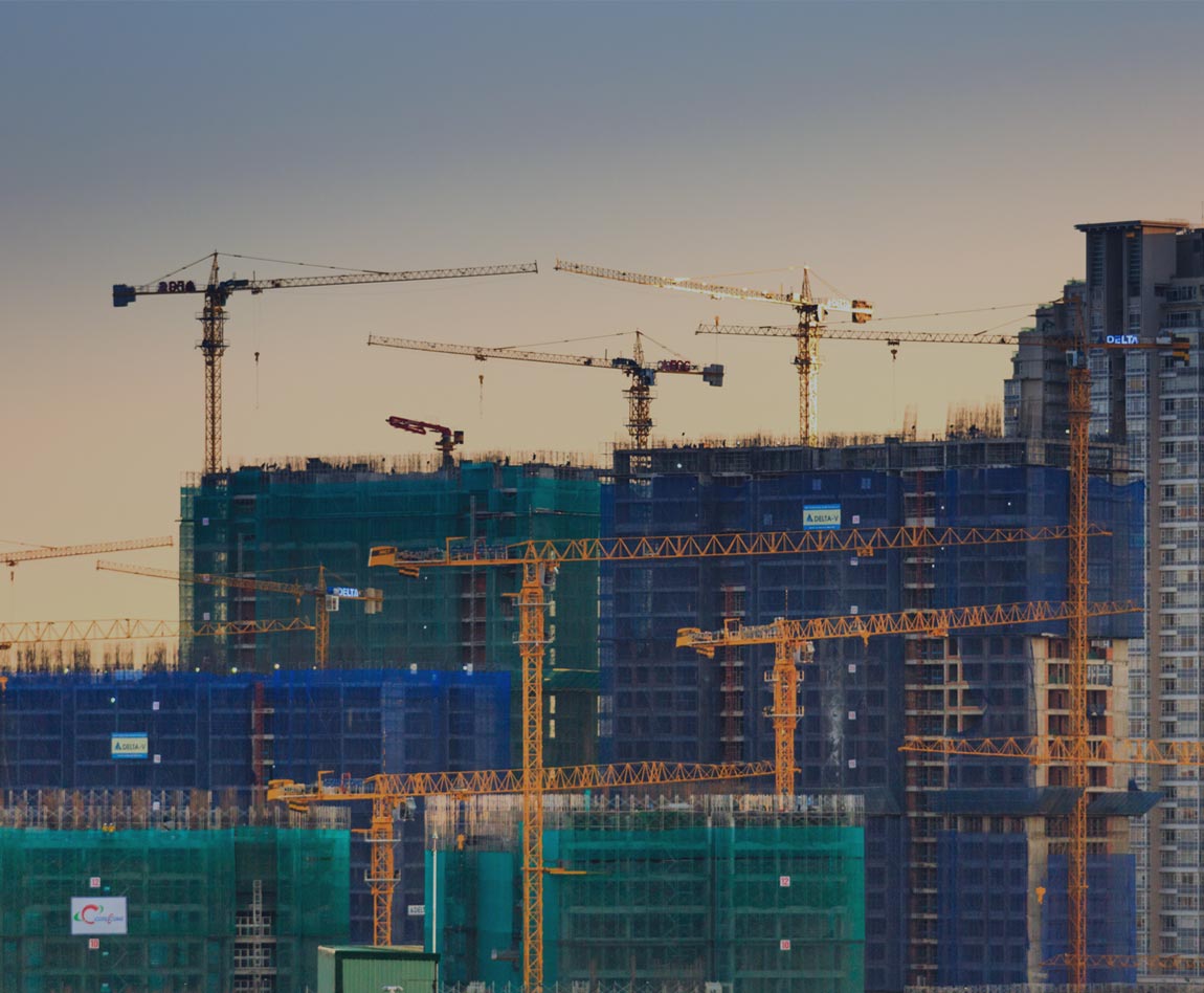 varias grúas frente a un gran complejo de edificios