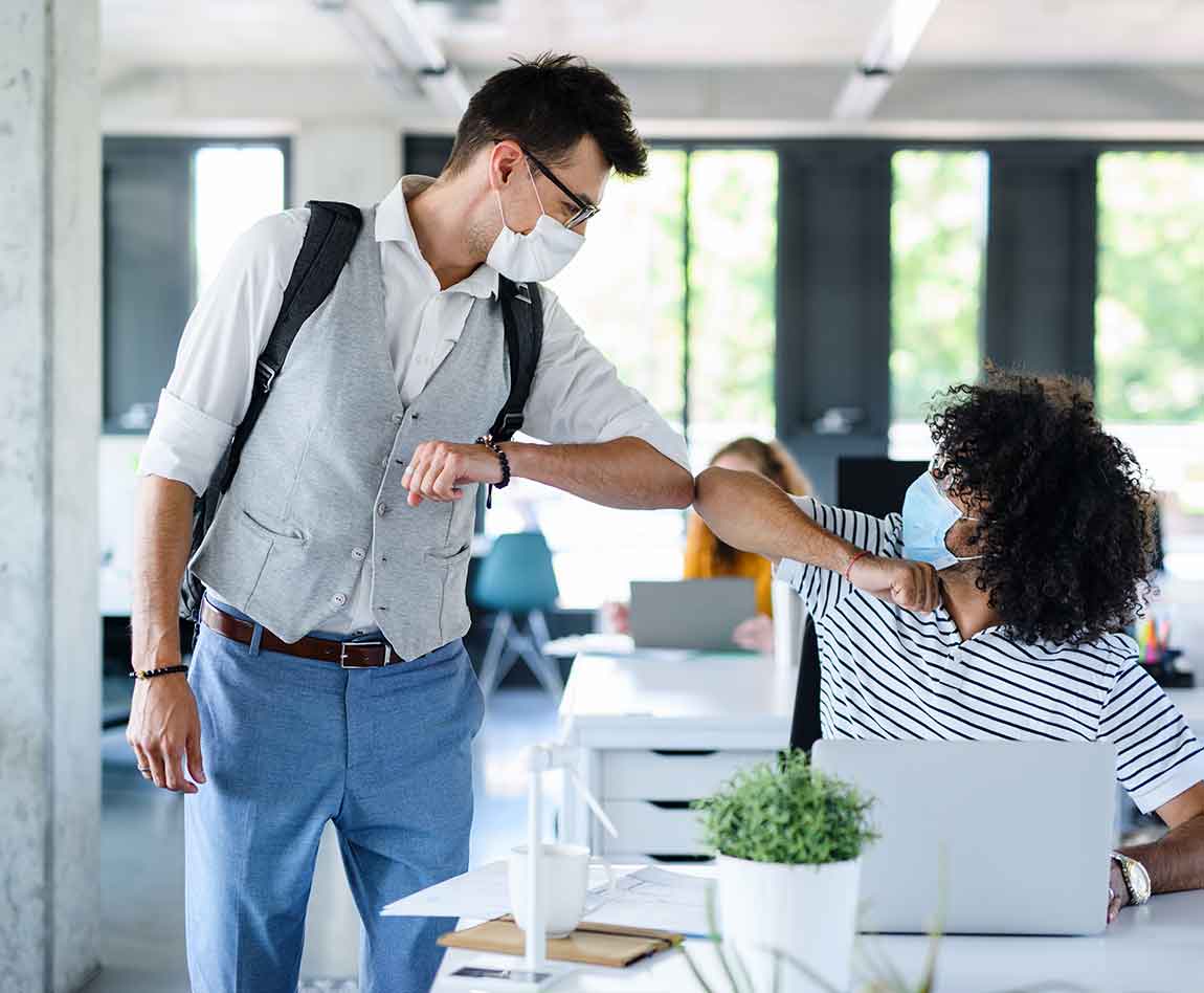 Deux collaborateurs avec des masques se tapent le coude
