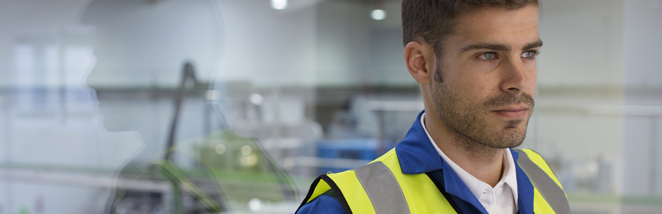 Travailleur debout près d'une fenêtre dans une usine