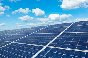 Des panneaux solaires en premier plan et le ciel bleu avec nuages en arrière plan