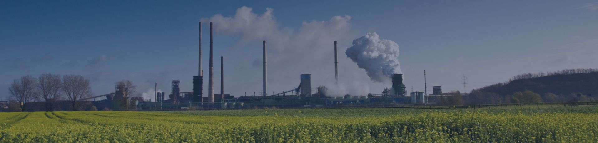 Vue d'un champ, une usine avec des cheminées en fonctionnement
