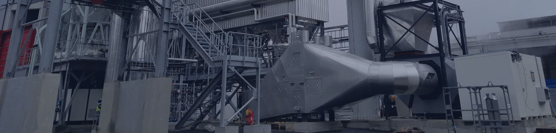 Usine industrielle moderne avec infrastructure métallisée et cheminée de filtration.