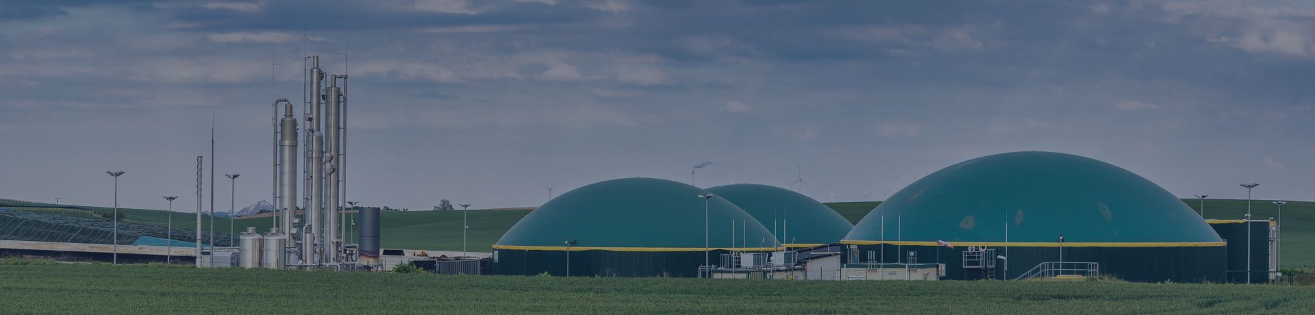 Usine de méthanisation ou de biométhane avec dômes verts et tours de distillation dans un champ.