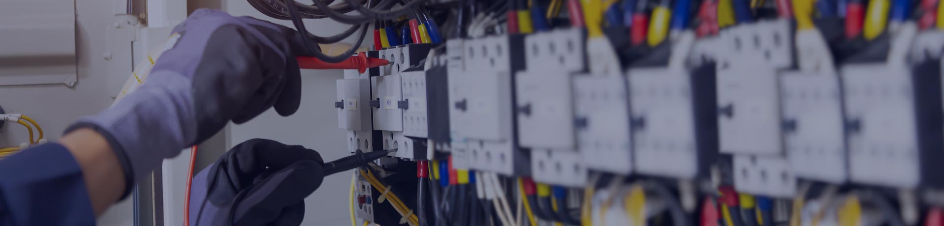 Une personne porte des gants et est en train de réaliser le contrôle d'une installation électrique basse tension