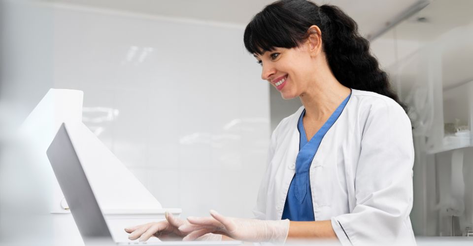 Professionnelle de santé utilisant un ordinateur pour la cybersécurité médicale.