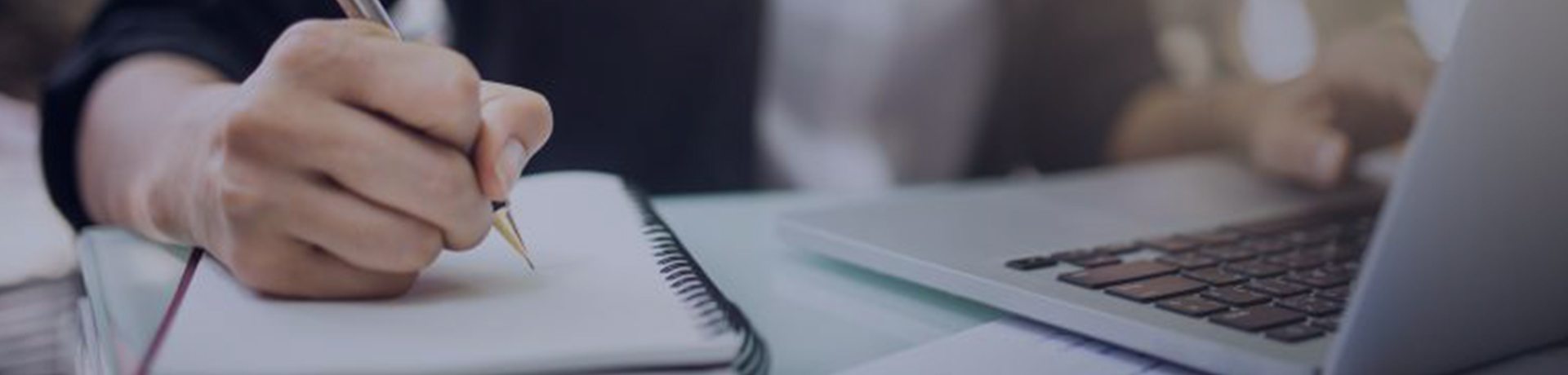 Une femme devant son ordinateur, écrit sur un bloc note