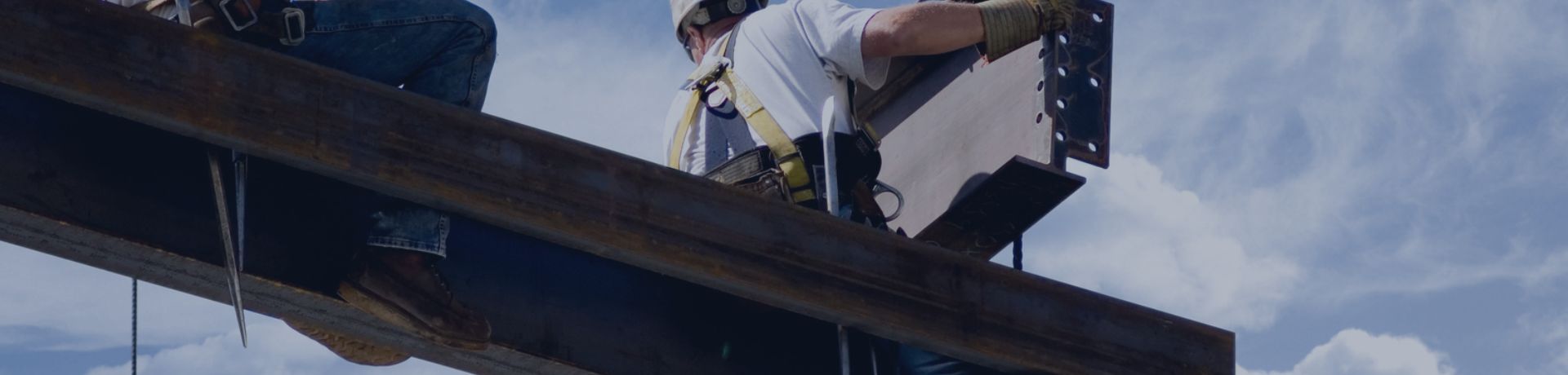 Ouvriers en hauteur installant une poutre métallique sur un chantier de construction.