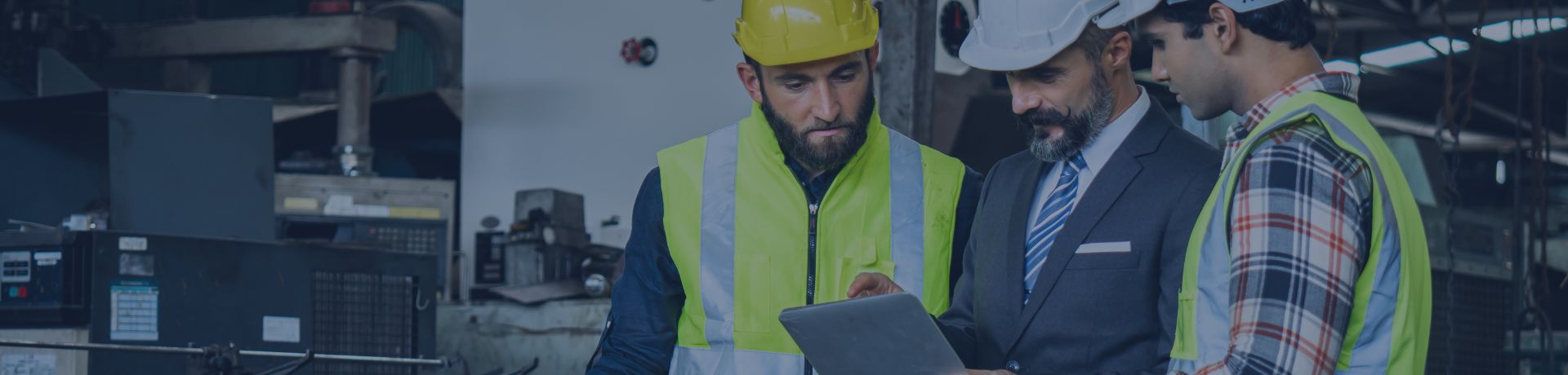 3 hommes avec des casques de sécurité blanc regardent une tablette