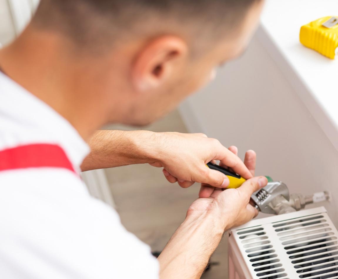 Un homme réalise l'entretien d'un radiateur