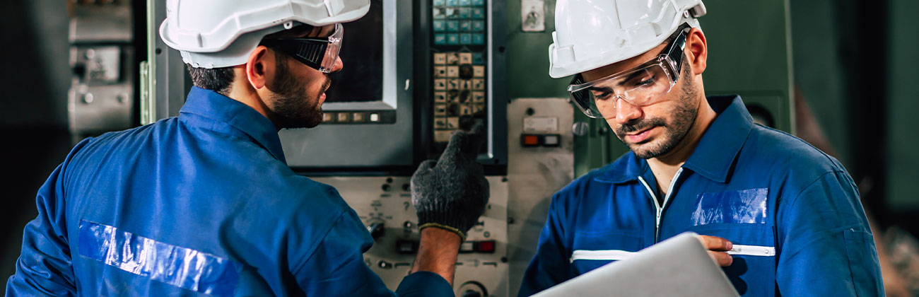 L'équipe d'ingénieurs industriels contrôle les machines lourdes à l'aide d'un ordinateur portable pour aider à analyser les problèmes de fonctionnement.
