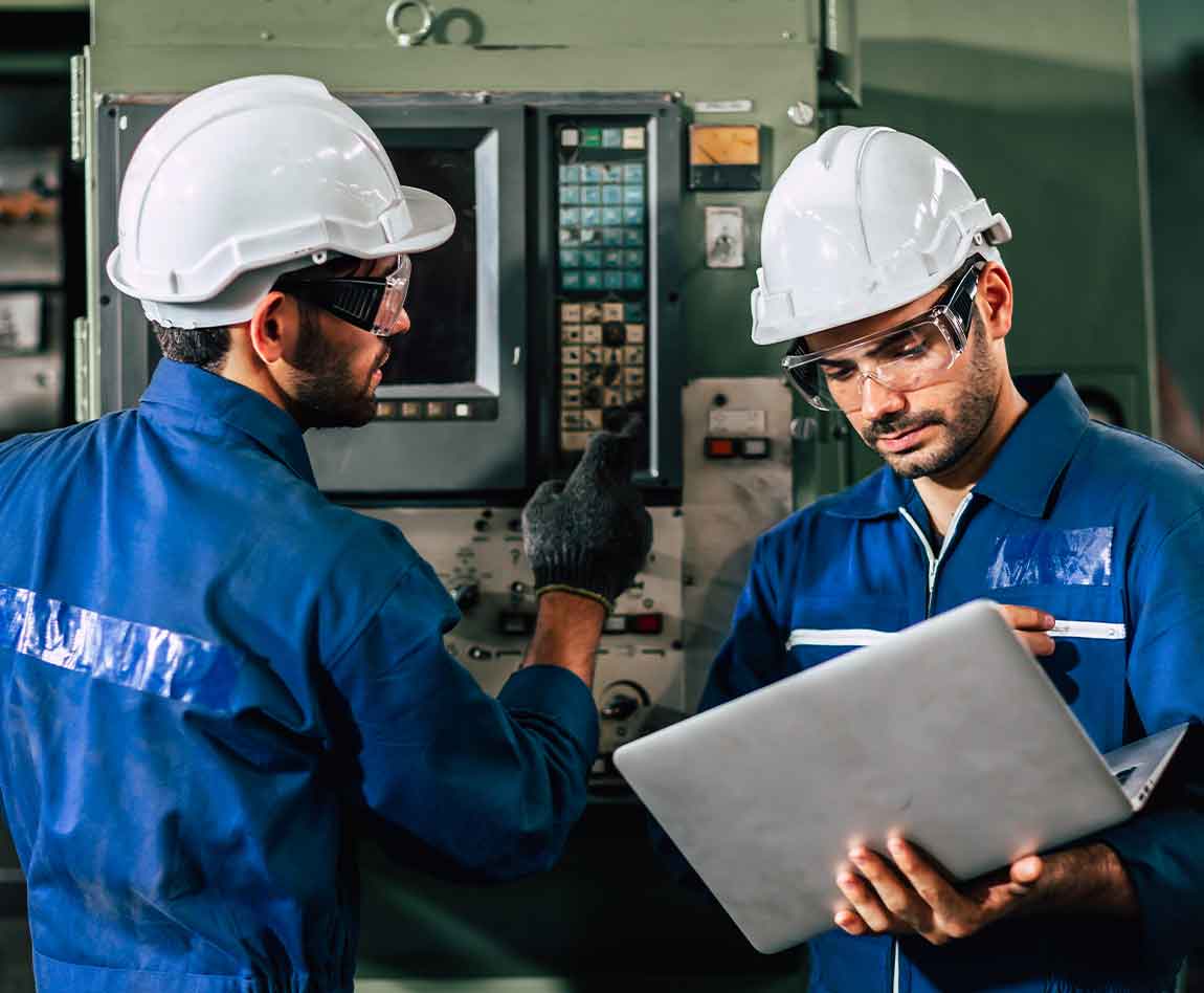 L'équipe d'ingénieurs industriels contrôle les machines lourdes à l'aide d'un ordinateur portable pour aider à analyser les problèmes de fonctionnement.