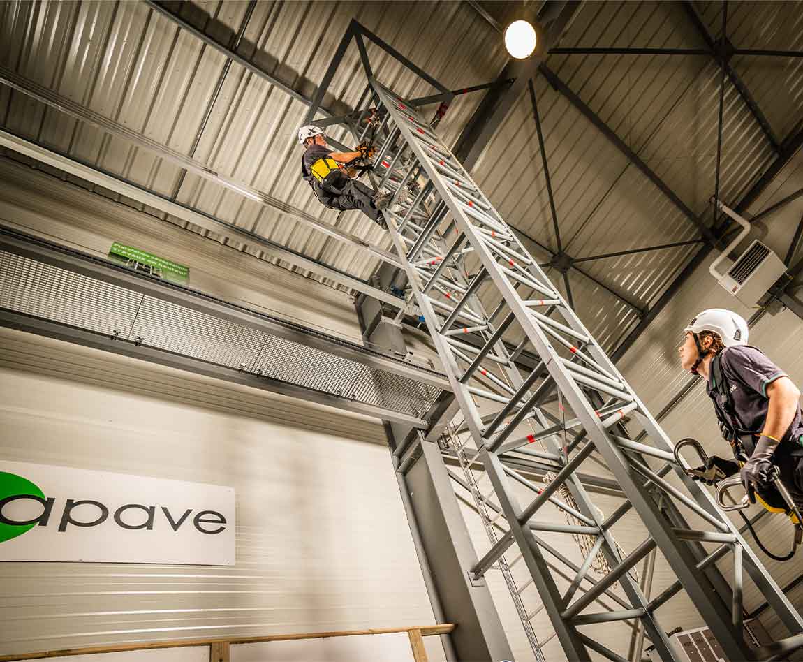 Deux stagiaires apave munis de harnais de sécurité montent une tour