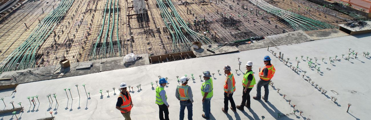 Sept hommes avec des casques et des gilets jaunes sur un chantier de construction