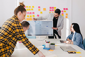 Un homme debout derrière un écran plat d'ordinateur entouré de son équipe