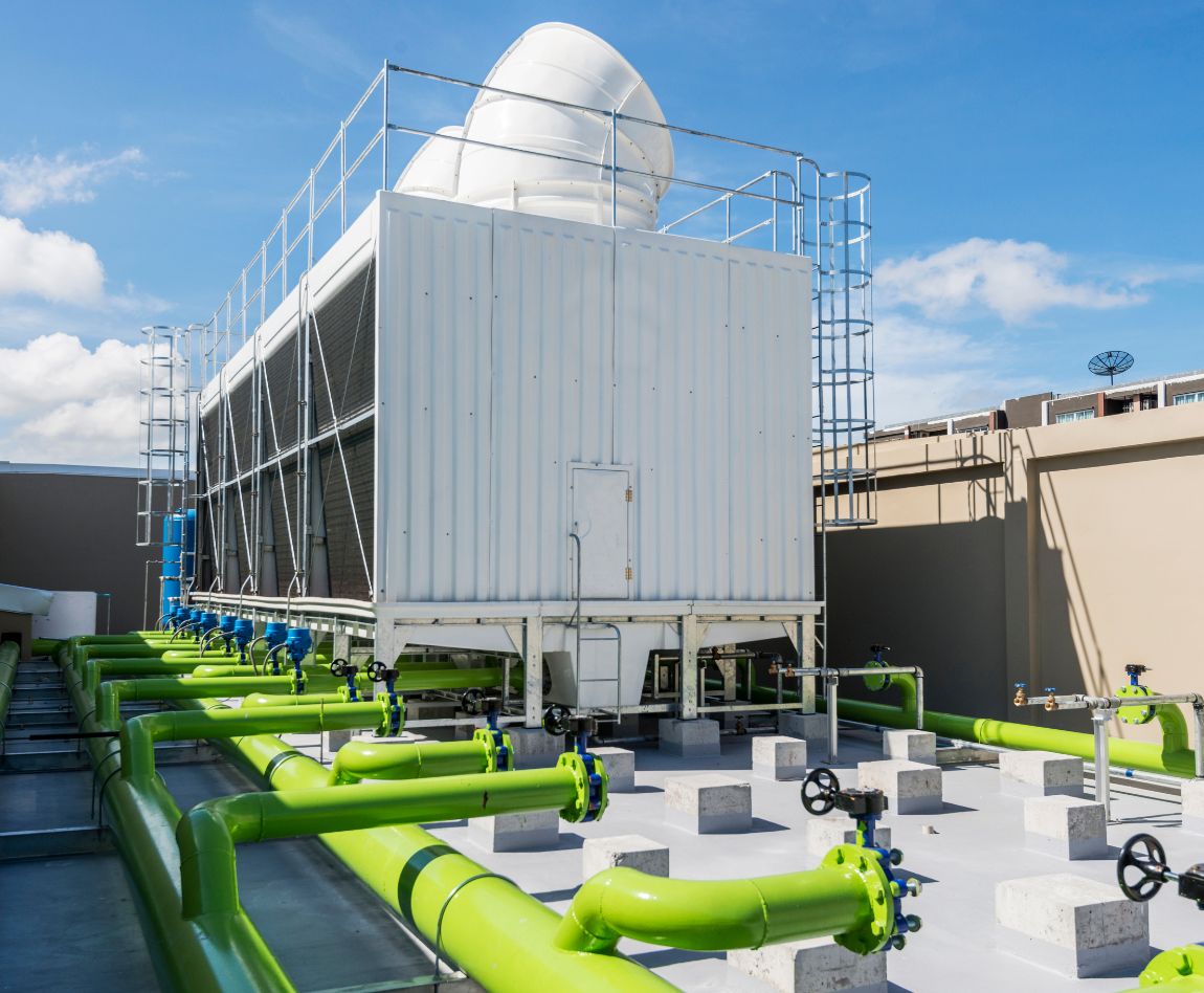 Des tuyaux verts connectés à une tour de refroidissement blanche sur un toit, illustrant un système de climatisation industriel.