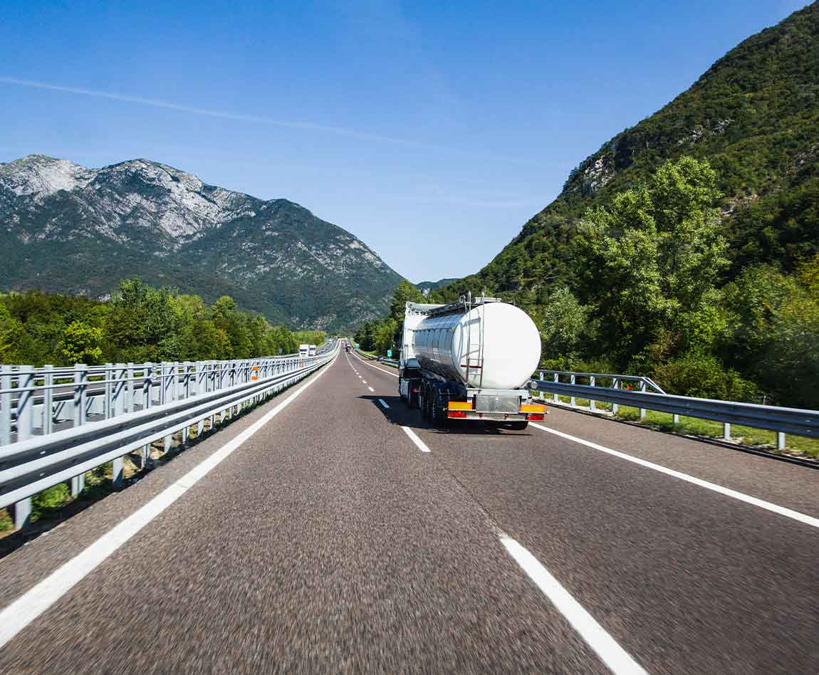 Un camion citerne roule sur l'autoroute avec une vue des Alpes en arrière plan.