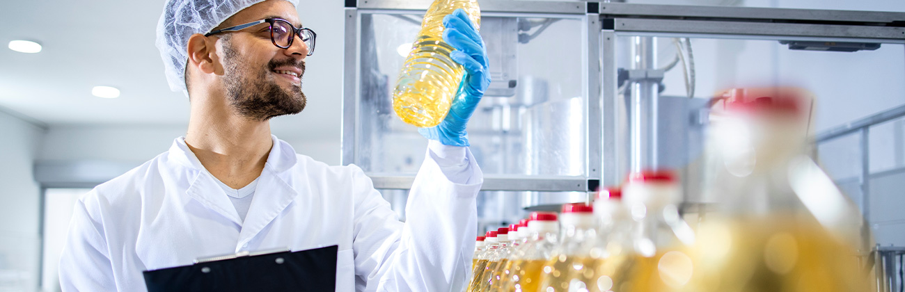 Un employé d'une usine contrôle une ligne de production de bouteilles d'huile