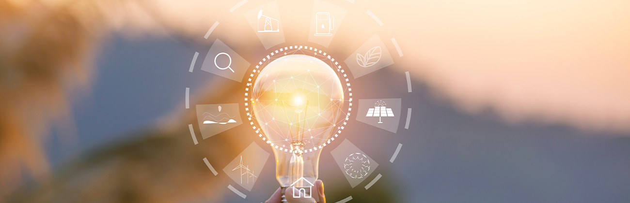 Main tenant une ampoule avec des pictogrammes représentant des sources d'énergie renouvelables