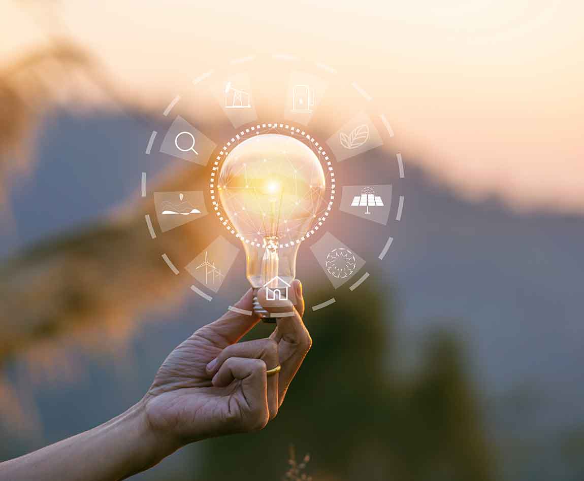 Main tenant une ampoule avec des pictogrammes représentant des sources d'énergie renouvelables