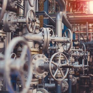 Une vue rapprochée sur des vannes de régulation et des tuyaux de plomberie industrielle en métal, avec un halo de lumière chaude en arrière-plan