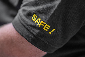 une manche de t shirt gris avec le mot Safe en jaune