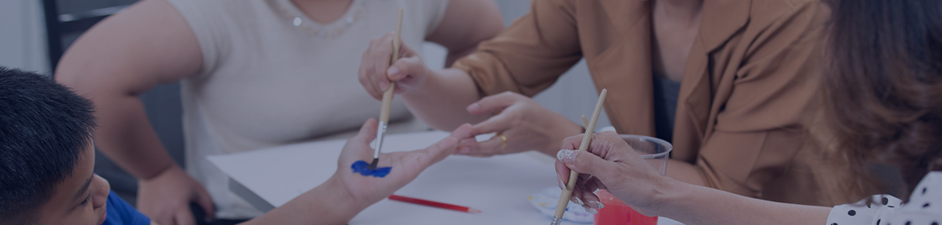 Une aide soignante en train d'aider des enfants handicapés à faire de la peinture