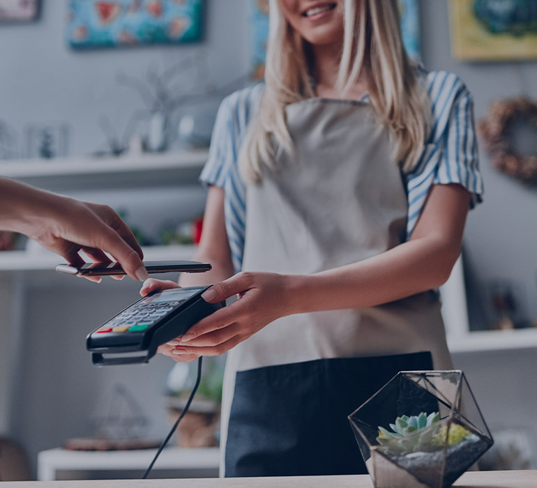 Une fleuriste tend un appareil bancaire à son client