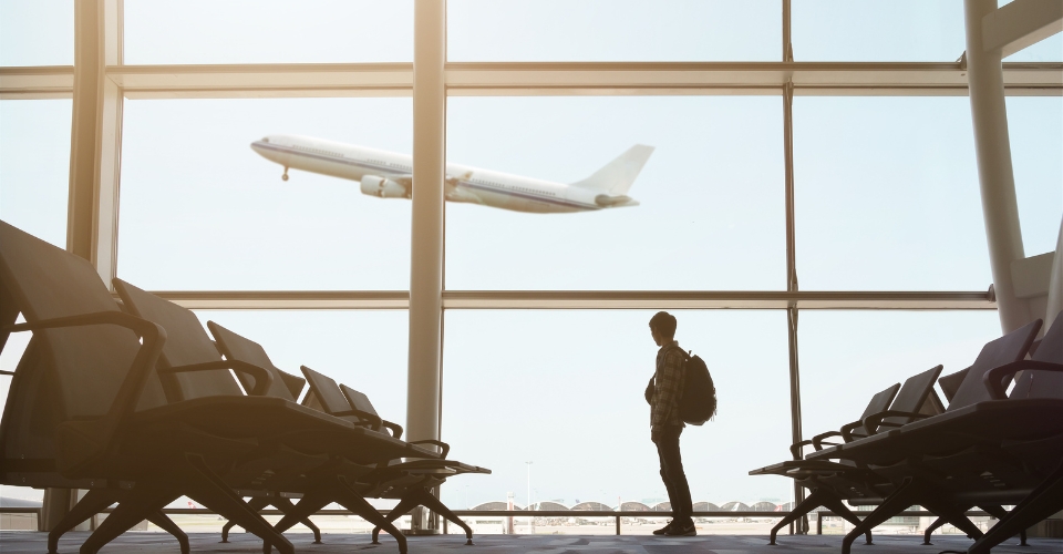 Une personne dans un aéroport regarde un décollage d'avion.