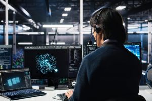Expert en cybersécurité avec casque travaillant sur des flux de données complexes face à des écrans.