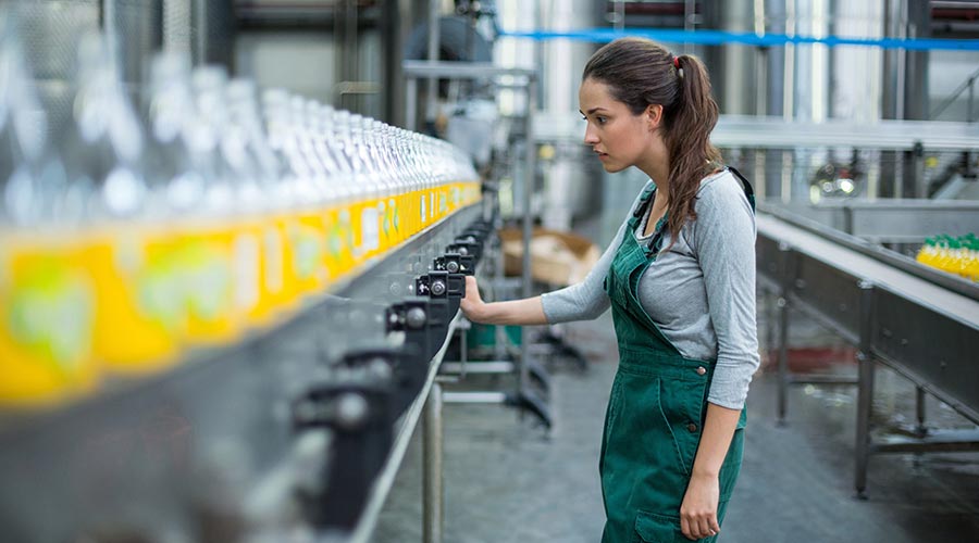 Une femme avec un tablier en train de contrôler une ligne de production