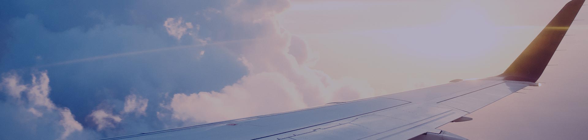 An aircraft wing in the sky with clouds in the background