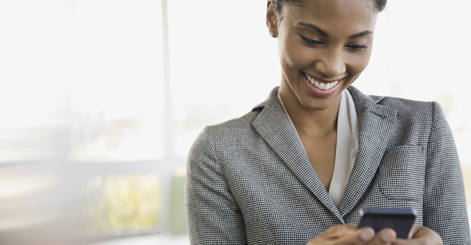 Une jeune femme sourit en regardant son téléphone
